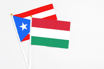 Hungary and Puerto Rico stick flags on white background. High quality fabric, miniature national flag. Peaceful global concept.White floor for copy space.