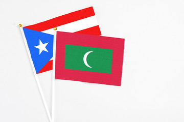 Maldives and Puerto Rico stick flags on white background. High quality fabric, miniature national flag. Peaceful global concept.White floor for copy space.
