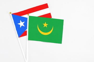 Mauritania and Puerto Rico stick flags on white background. High quality fabric, miniature national flag. Peaceful global concept.White floor for copy space.