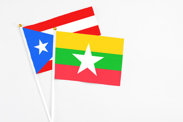 Fototapeta premium Myanmar and Puerto Rico stick flags on white background. High quality fabric, miniature national flag. Peaceful global concept.White floor for copy space.