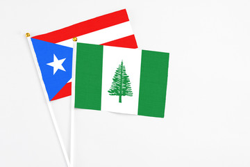 Norfolk Island and Puerto Rico stick flags on white background. High quality fabric, miniature national flag. Peaceful global concept.White floor for copy space.