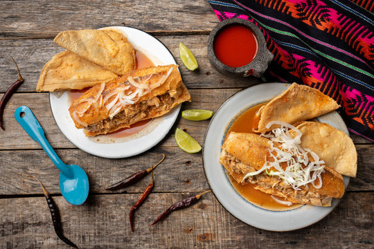 Mexican drowned sandwich also called "torta ahogada" with red sauce on wooden background