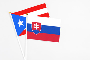 Slovakia and Puerto Rico stick flags on white background. High quality fabric, miniature national flag. Peaceful global concept.White floor for copy space.