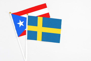 Sweden and Puerto Rico stick flags on white background. High quality fabric, miniature national flag. Peaceful global concept.White floor for copy space.