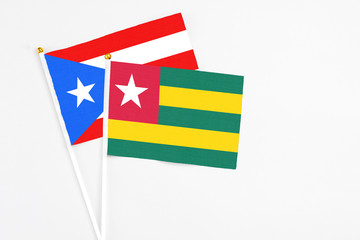 Togo and Puerto Rico stick flags on white background. High quality fabric, miniature national flag. Peaceful global concept.White floor for copy space.