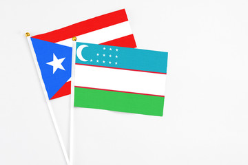 Uzbekistan and Puerto Rico stick flags on white background. High quality fabric, miniature national flag. Peaceful global concept.White floor for copy space.