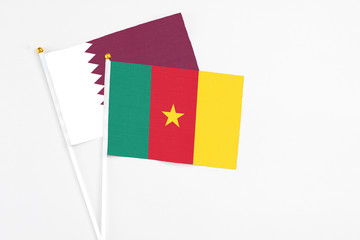 Cameroon and Qatar stick flags on white background. High quality fabric, miniature national flag. Peaceful global concept.White floor for copy space.