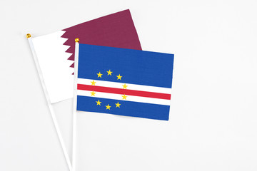Cape Verde and Qatar stick flags on white background. High quality fabric, miniature national flag. Peaceful global concept.White floor for copy space.