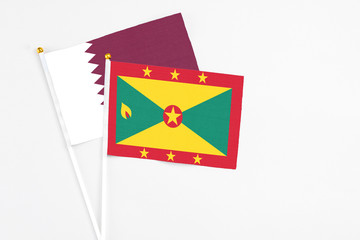 Grenada and Qatar stick flags on white background. High quality fabric, miniature national flag. Peaceful global concept.White floor for copy space.