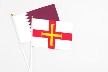 Guernsey and Qatar stick flags on white background. High quality fabric, miniature national flag. Peaceful global concept.White floor for copy space.