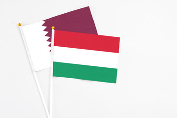 Hungary and Qatar stick flags on white background. High quality fabric, miniature national flag. Peaceful global concept.White floor for copy space.
