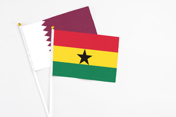 Ghana and Qatar stick flags on white background. High quality fabric, miniature national flag. Peaceful global concept.White floor for copy space.