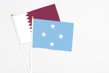 Micronesia and Qatar stick flags on white background. High quality fabric, miniature national flag. Peaceful global concept.White floor for copy space.