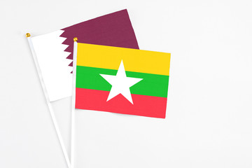 Myanmar and Qatar stick flags on white background. High quality fabric, miniature national flag. Peaceful global concept.White floor for copy space.