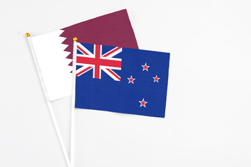 Fototapeta premium New Zealand and Qatar stick flags on white background. High quality fabric, miniature national flag. Peaceful global concept.White floor for copy space.