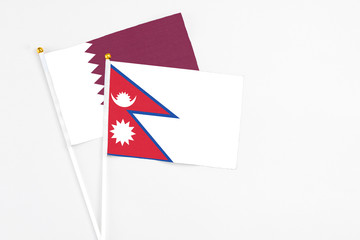 Fototapeta na wymiar Nepal and Qatar stick flags on white background. High quality fabric, miniature national flag. Peaceful global concept.White floor for copy space.