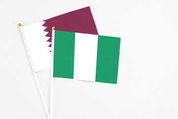 Nigeria and Qatar stick flags on white background. High quality fabric, miniature national flag. Peaceful global concept.White floor for copy space.