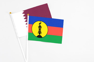 New Caledonia and Qatar stick flags on white background. High quality fabric, miniature national flag. Peaceful global concept.White floor for copy space.