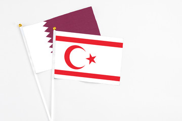 Northern Cyprus and Qatar stick flags on white background. High quality fabric, miniature national flag. Peaceful global concept.White floor for copy space.