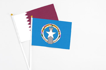 Northern Mariana Islands and Qatar stick flags on white background. High quality fabric, miniature national flag. Peaceful global concept.White floor for copy space.