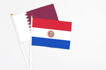 Paraguay and Qatar stick flags on white background. High quality fabric, miniature national flag. Peaceful global concept.White floor for copy space.