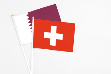 Switzerland and Qatar stick flags on white background. High quality fabric, miniature national flag. Peaceful global concept.White floor for copy space.