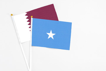 Somalia and Qatar stick flags on white background. High quality fabric, miniature national flag. Peaceful global concept.White floor for copy space.