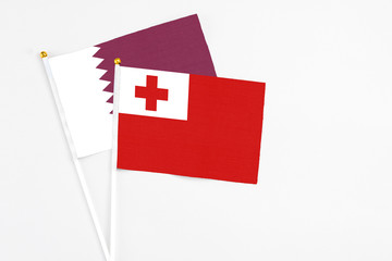 Tonga and Qatar stick flags on white background. High quality fabric, miniature national flag. Peaceful global concept.White floor for copy space.