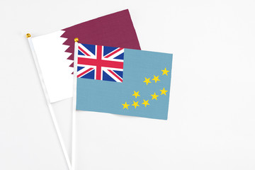 Fototapeta premium Tuvalu and Qatar stick flags on white background. High quality fabric, miniature national flag. Peaceful global concept.White floor for copy space.