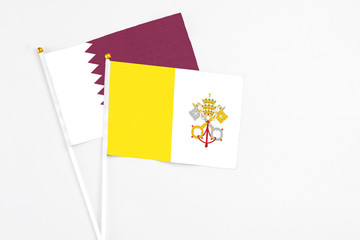 Vatican City and Qatar stick flags on white background. High quality fabric, miniature national flag. Peaceful global concept.White floor for copy space.