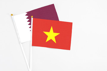 Vietnam and Qatar stick flags on white background. High quality fabric, miniature national flag. Peaceful global concept.White floor for copy space.