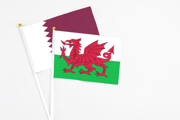 Wales and Qatar stick flags on white background. High quality fabric, miniature national flag. Peaceful global concept.White floor for copy space.