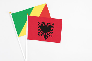 Obraz premium Albania and Republic Of The Congo stick flags on white background. High quality fabric, miniature national flag. Peaceful global concept.White floor for copy space.