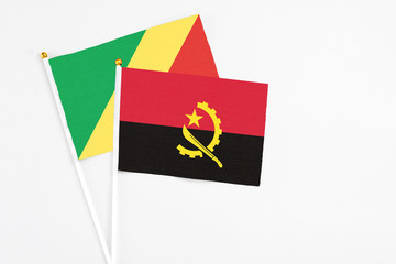 Angola and Republic Of The Congo stick flags on white background. High quality fabric, miniature national flag. Peaceful global concept.White floor for copy space.