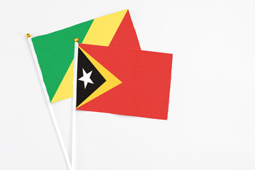 East Timor and Republic Of The Congo stick flags on white background. High quality fabric, miniature national flag. Peaceful global concept.White floor for copy space.