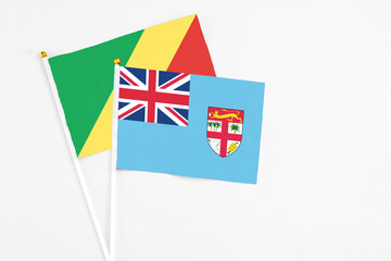 Fototapeta premium Fiji and Republic Of The Congo stick flags on white background. High quality fabric, miniature national flag. Peaceful global concept.White floor for copy space.