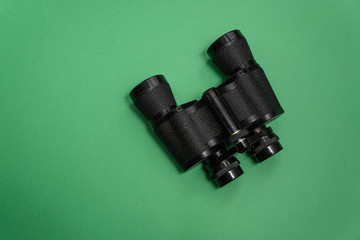 Old black binoculars on green background