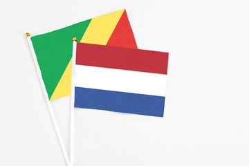 Netherlands and Republic Of The Congo stick flags on white background. High quality fabric, miniature national flag. Peaceful global concept.White floor for copy space.