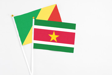 Suriname and Republic Of The Congo stick flags on white background. High quality fabric, miniature national flag. Peaceful global concept.White floor for copy space.