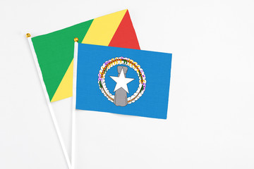 Northern Mariana Islands and Republic Of The Congo stick flags on white background. High quality fabric, miniature national flag. Peaceful global concept.White floor for copy space.