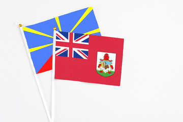 Fototapeta premium Bermuda and Reunion stick flags on white background. High quality fabric, miniature national flag. Peaceful global concept.White floor for copy space.