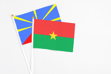 Burkina Faso and Reunion stick flags on white background. High quality fabric, miniature national flag. Peaceful global concept.White floor for copy space.