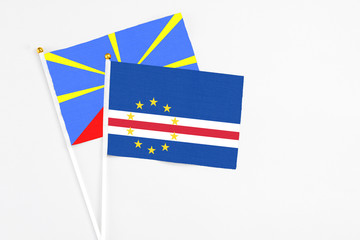 Cape Verde and Reunion stick flags on white background. High quality fabric, miniature national flag. Peaceful global concept.White floor for copy space.