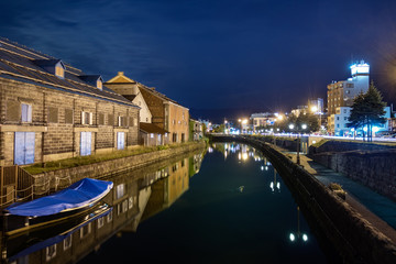 Fototapeta na wymiar Night view of the Otaru canal and an old warehouse next to the port in Otaru, Japan.