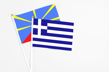 Obraz premium Greece and Reunion stick flags on white background. High quality fabric, miniature national flag. Peaceful global concept.White floor for copy space.