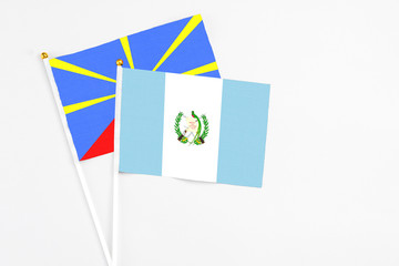 Guatemala and Reunion stick flags on white background. High quality fabric, miniature national flag. Peaceful global concept.White floor for copy space.