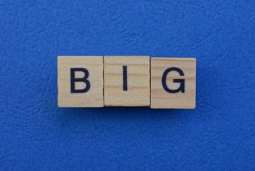 word big made from brown wooden letters lies on a blue table