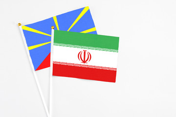 Iran and Reunion stick flags on white background. High quality fabric, miniature national flag. Peaceful global concept.White floor for copy space.