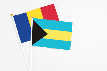 Bahamas and Romania stick flags on white background. High quality fabric, miniature national flag. Peaceful global concept.White floor for copy space.