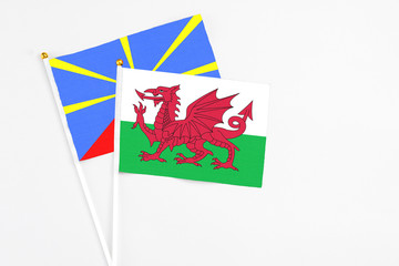 Wales and Reunion stick flags on white background. High quality fabric, miniature national flag. Peaceful global concept.White floor for copy space.